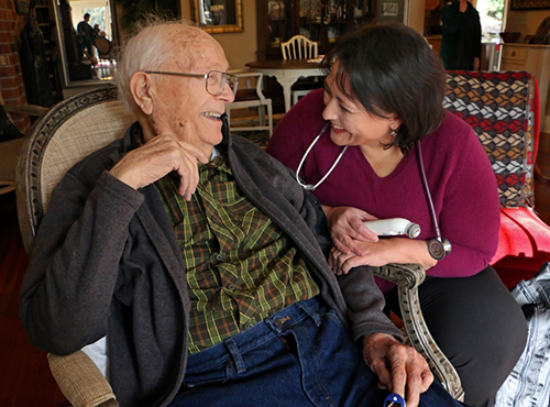 A patient smiling at his health care provider during a medical house call in his home