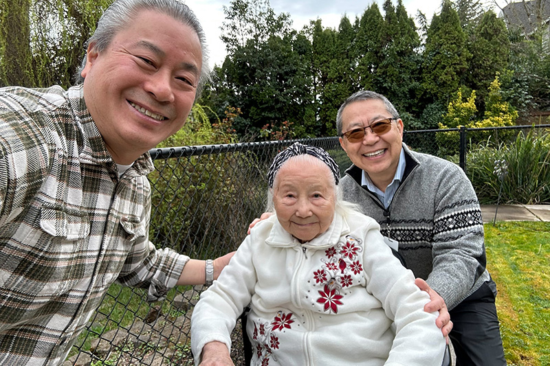 A Housecall Providers patient smiles for a photo between her son and spiritual counselor