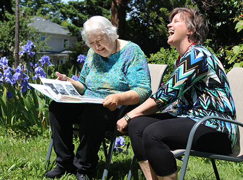 Hospice volunteer laughing while looking at a photo album with her patient